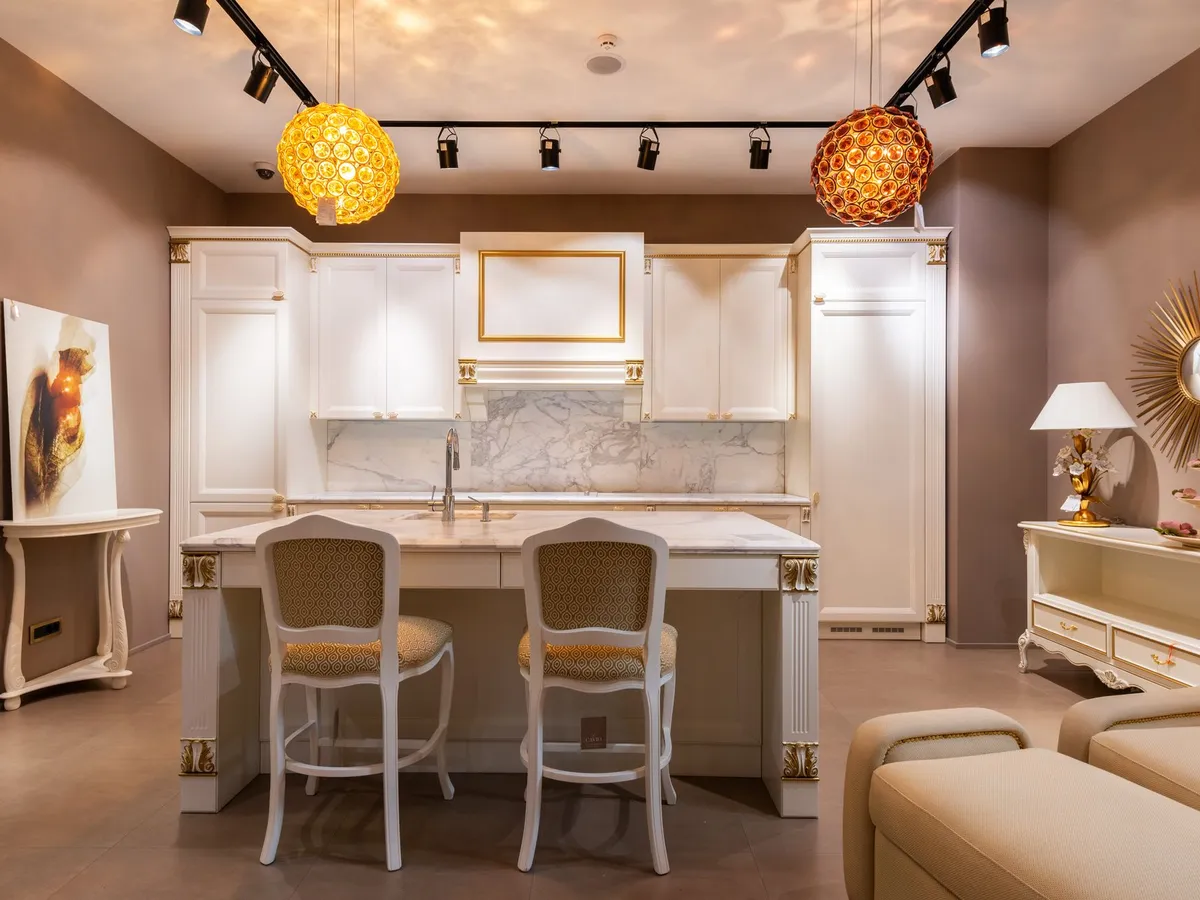 Showroom kitchen with white cabinets, a veined white stone island counter and a matching stone backsplash