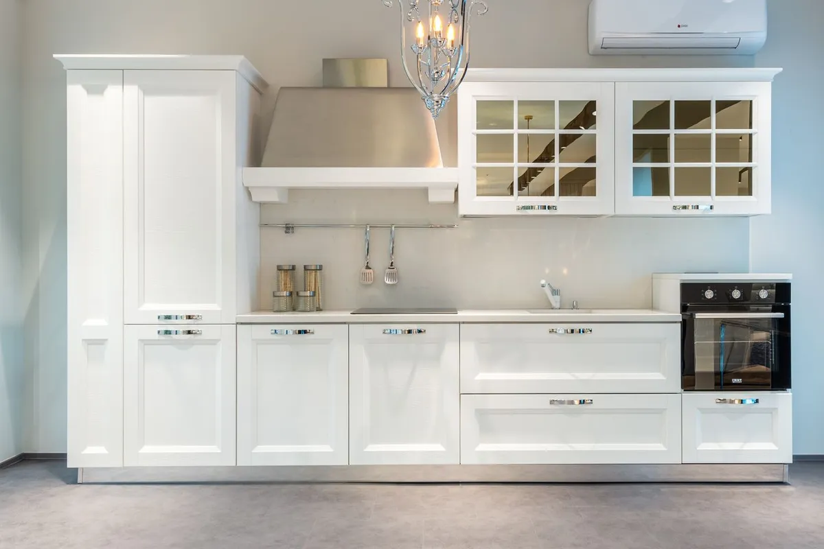 A trapezoid chimney hood over the cooktop: the unit price climbs with width and finish, while the labor only jumps when the duct route has to be built rather than reused