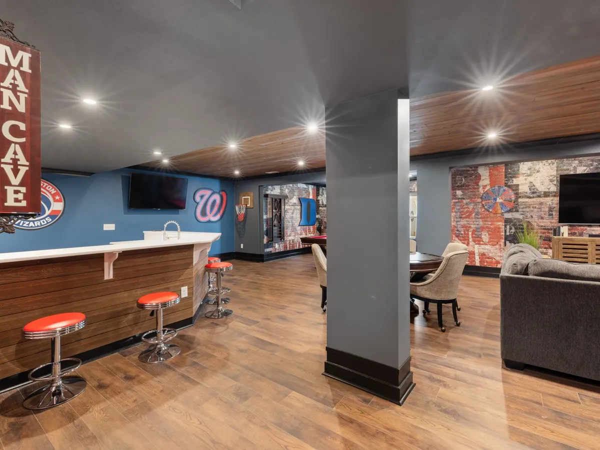 Finished basement recreation room lit by a run of recessed ceiling lights