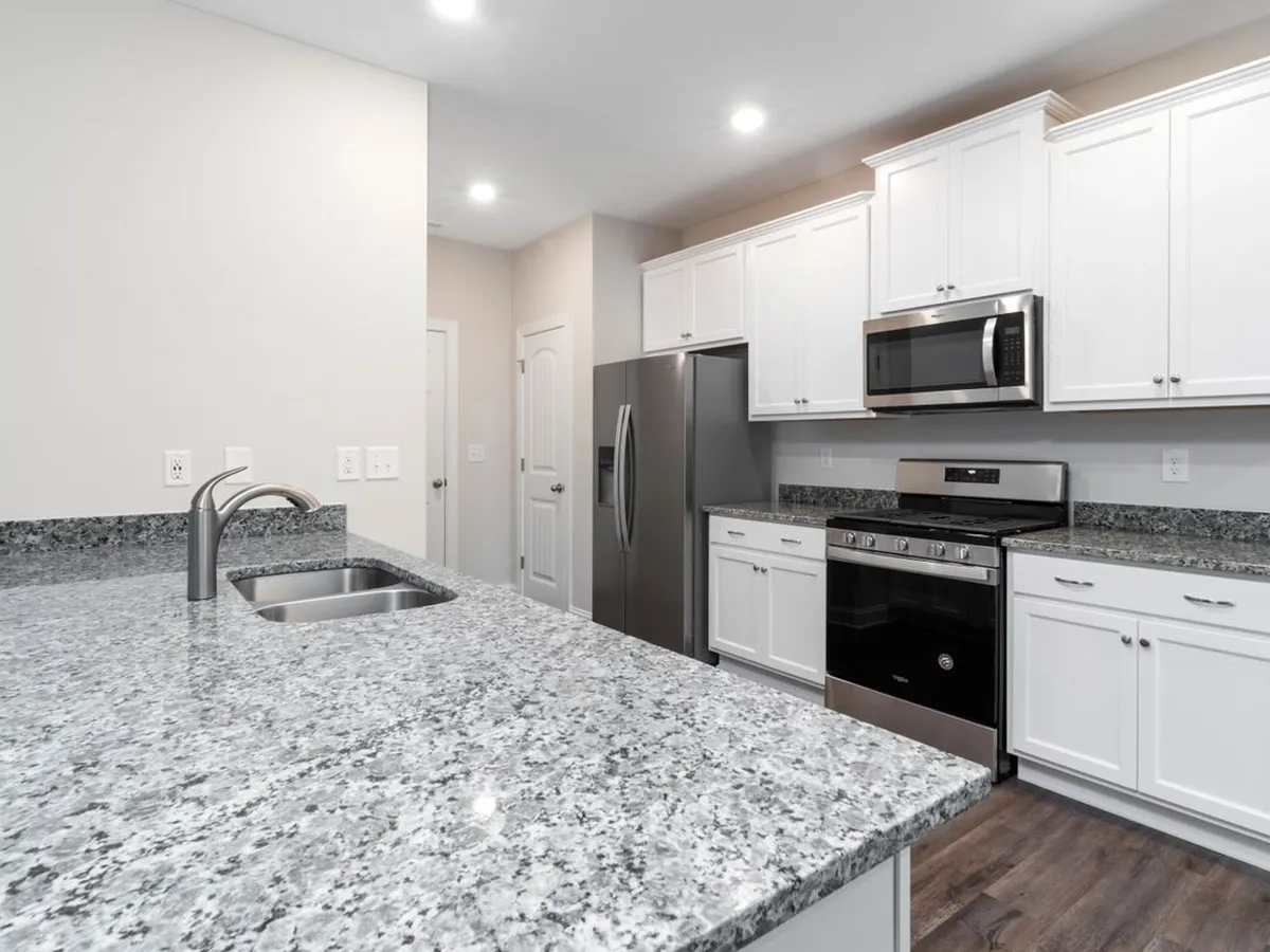White kitchen with a speckled grey island countertop and undermount sink in the foreground