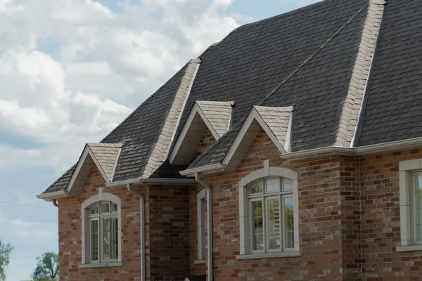 Brick house with a new architectural shingle roof, dormers and gutters