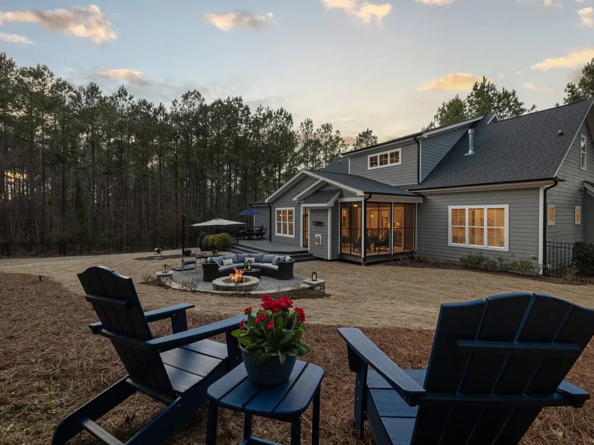 House on a wooded lot with a wide open yard at dusk