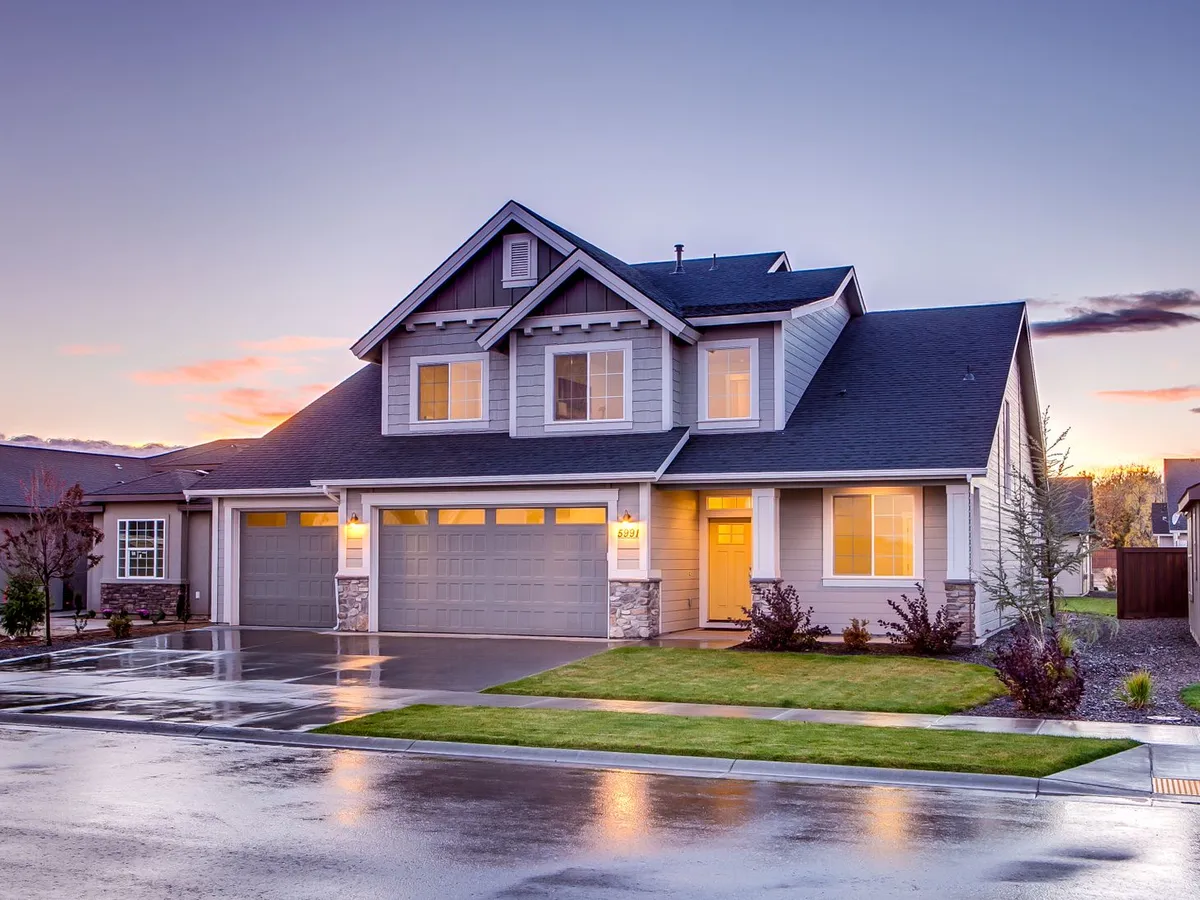 Two-story house with gray lap siding and two garage doors at dusk