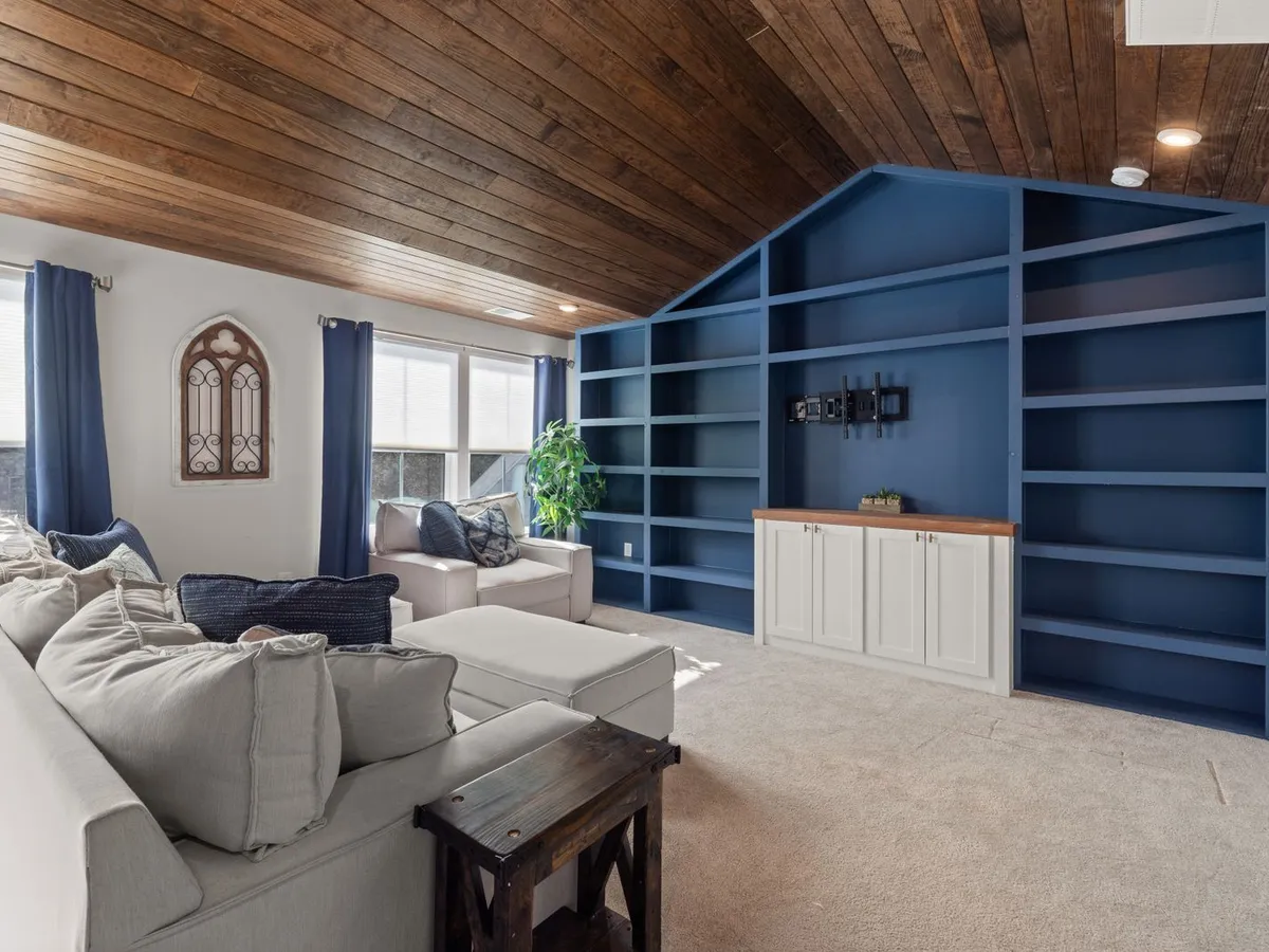 Living room with a vaulted wood-plank ceiling and built-in shelving