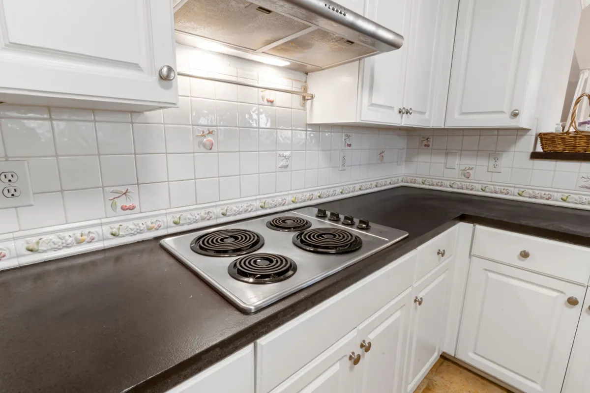 A dark counter with its cooktop cut into it in close view — cutouts and rounded corners are fabrication work on a brittle stone, priced inside the edges and cutouts line of the breakdown above.