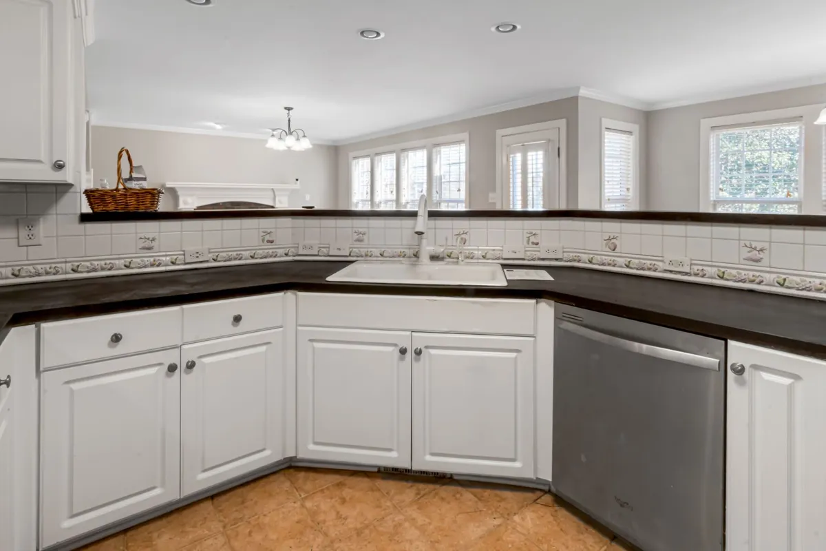 The same dark counters wrapping a corner sink run — slate material and fabrication are 55–65% of a slate budget, and a corner layout like this is priced by the square foot of slab, seams included. Captions describe the visible dark stone only; the pictured counters are not certified as slate.