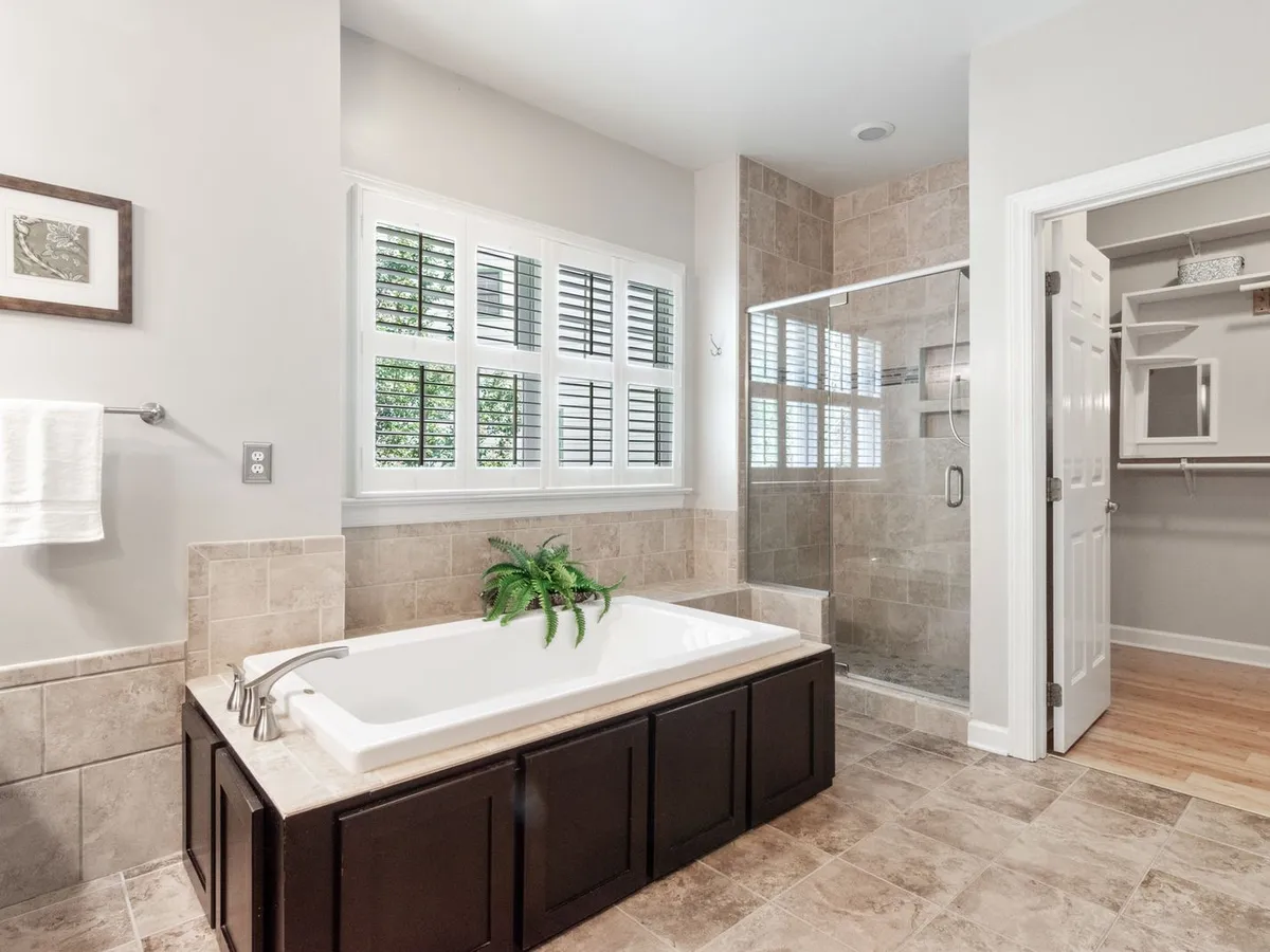 Bathroom with a large-format stone-look tile floor, a built-in tub and a glass-enclosed shower