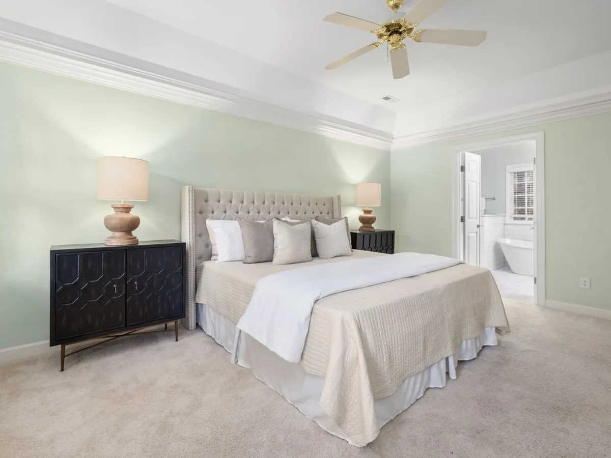 Bedroom with a tray ceiling, ceiling fan and carpeted floor