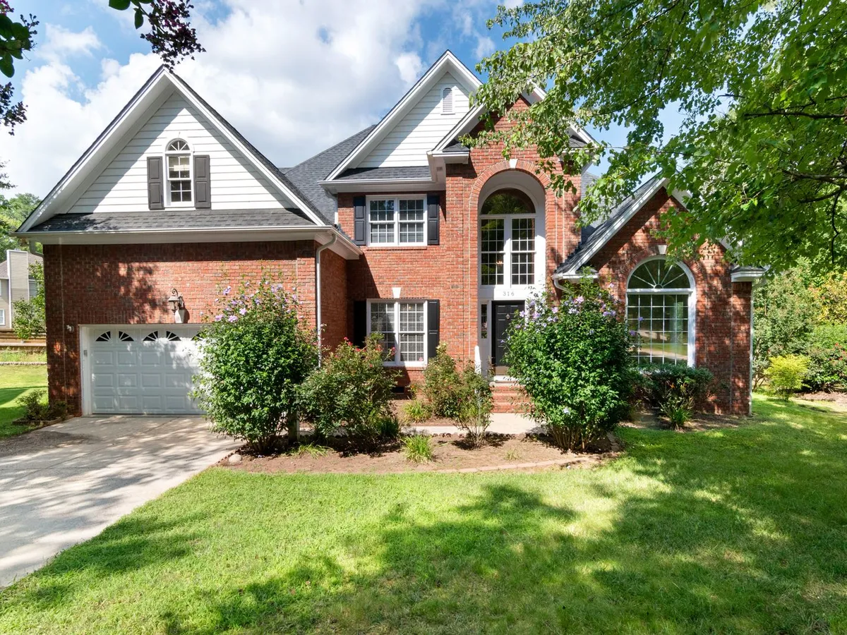 Brick house with a lush green front lawn and planting beds