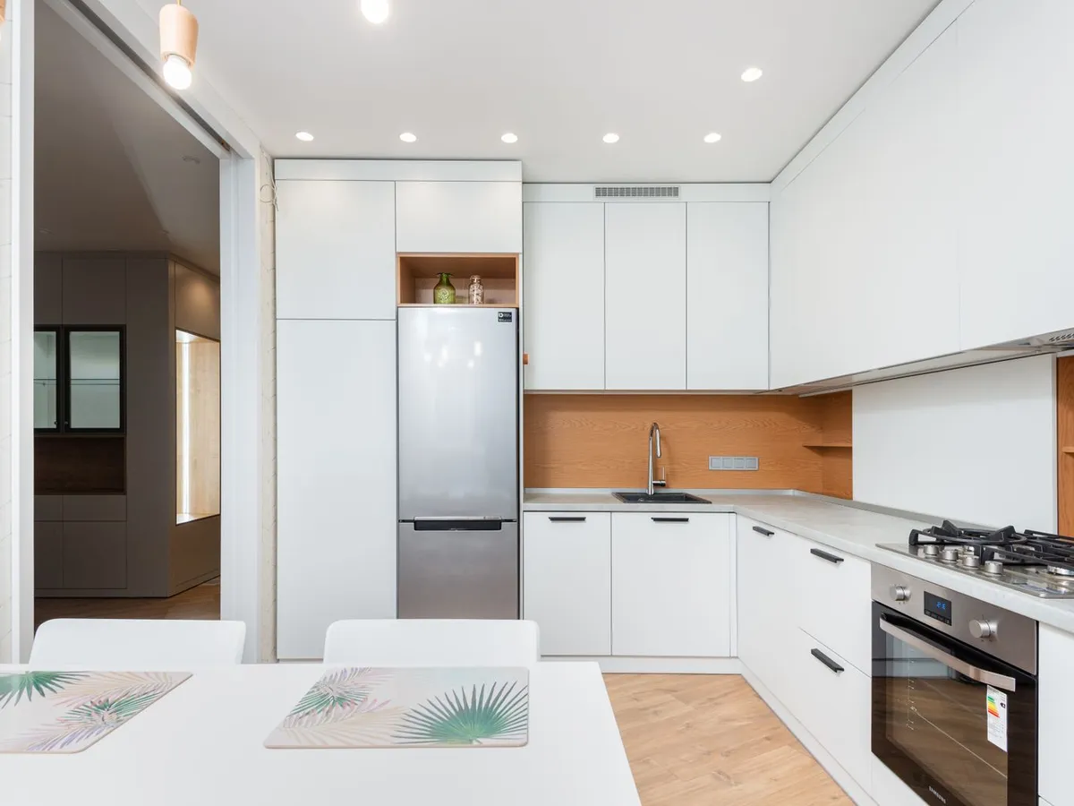 White kitchen with a stainless steel fridge and oven and light counters