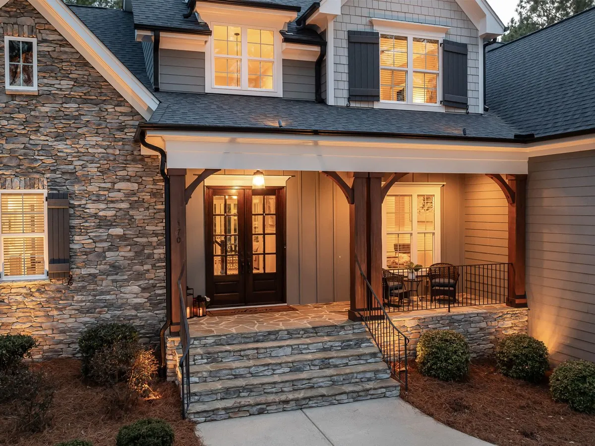 Stone house with a covered porch and dark double glass entry doors at dusk
