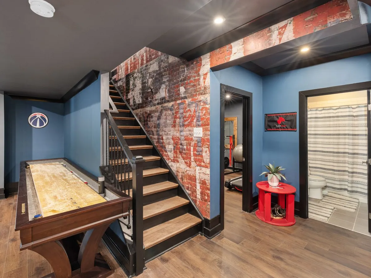 Finished basement recreation room with a staircase and wood-look flooring