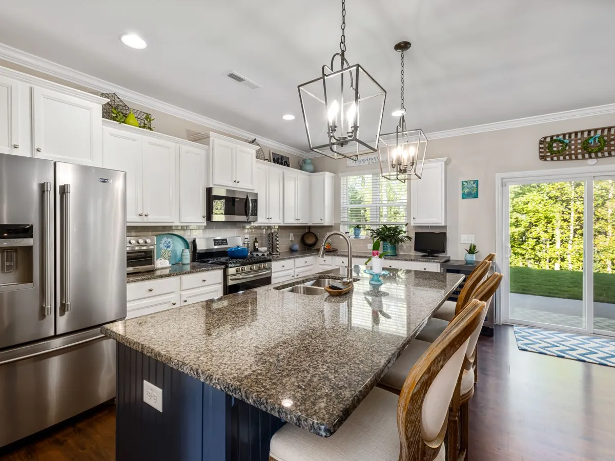 Kitchen island topped with a polished speckled stone-look counter, pendant lights above