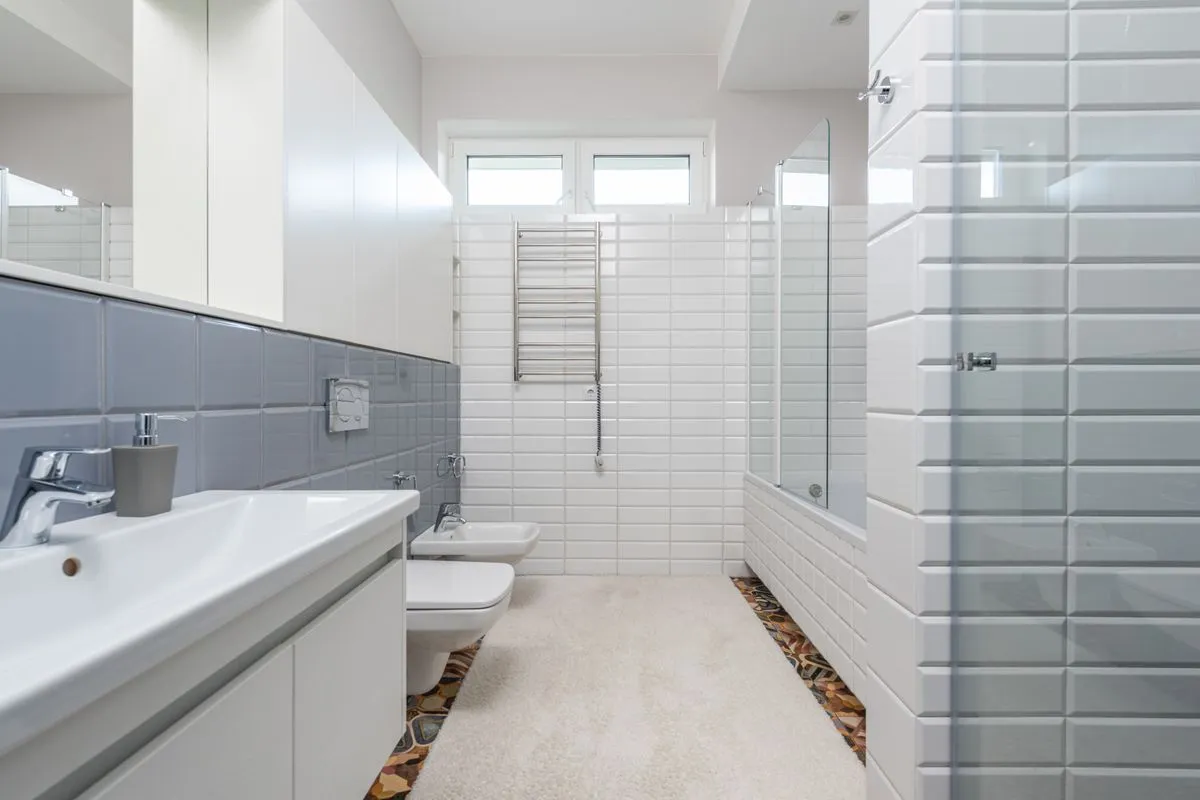 A bathroom with bevelled subway tile walls and a white vanity counter — grout is the tile counter's lifetime line: the tiles are non-porous, the joints between them are not.