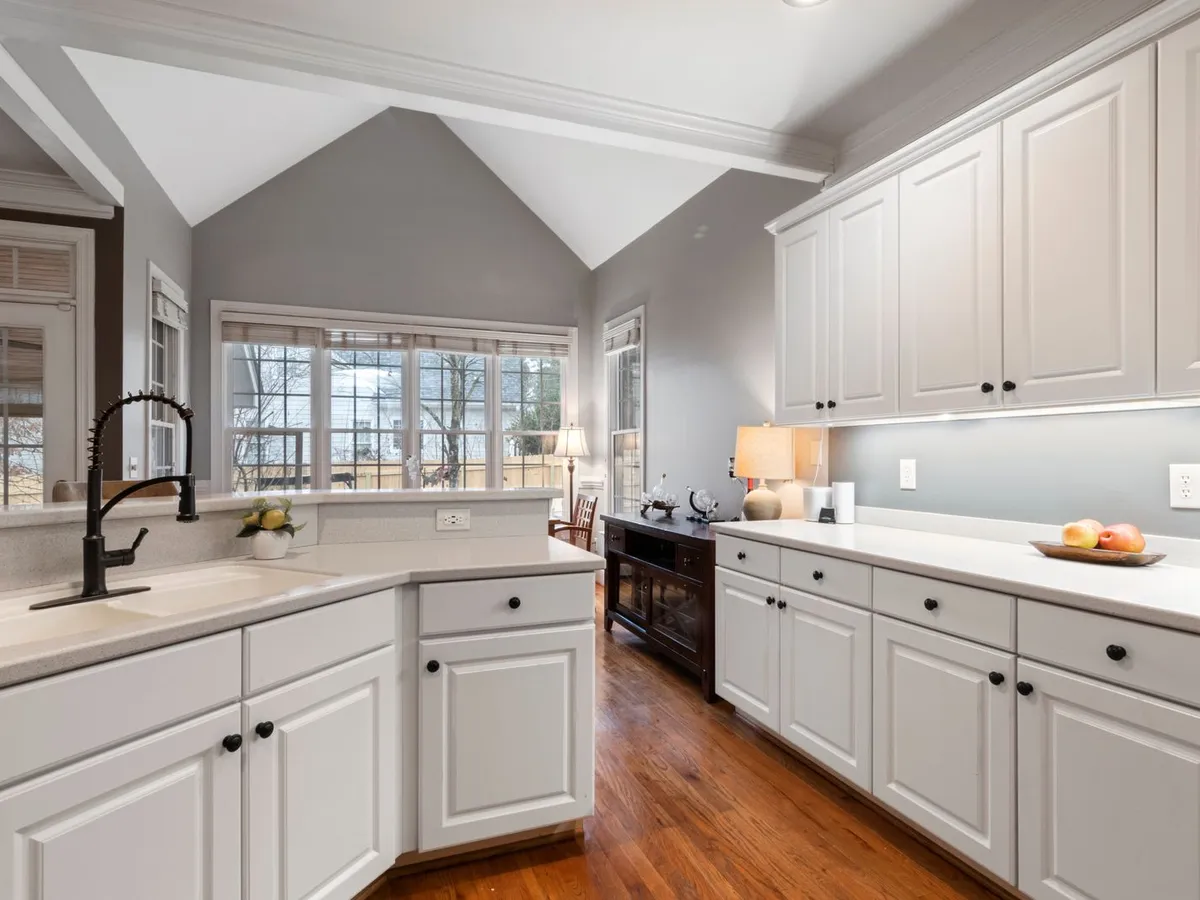 White kitchen with light speckled stone-look counters and a warm wood floor