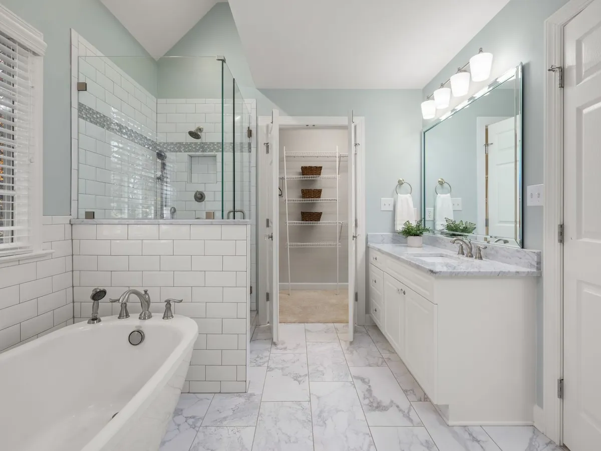Primary bathroom with a long white vanity, stone-look top and a wide mirror