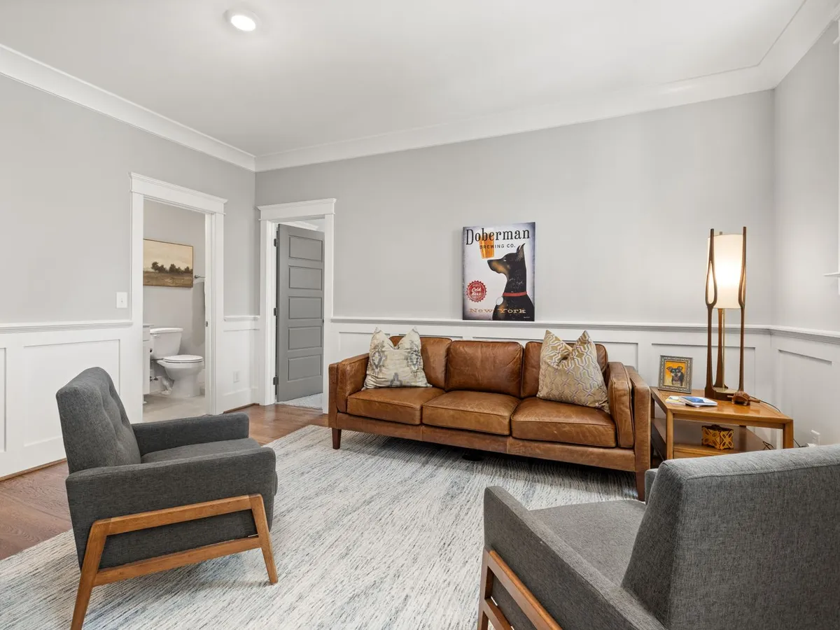 Living room with white flat-panel wainscoting on the walls and a leather sofa