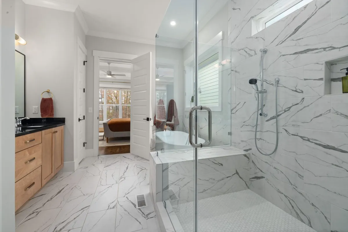 Glass is a priced choice, not a default: Angi prices a glass shower door at $550–$1,400 and Modernize puts frameless glass at $1,000–$3,000 or more on top of the base job