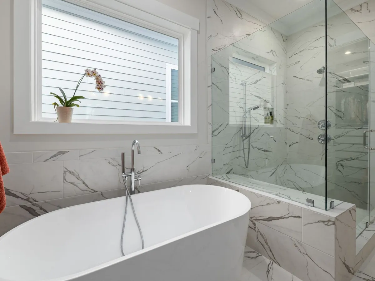Marble-look tiled bathroom with a glass-enclosed walk-in shower beside a freestanding tub