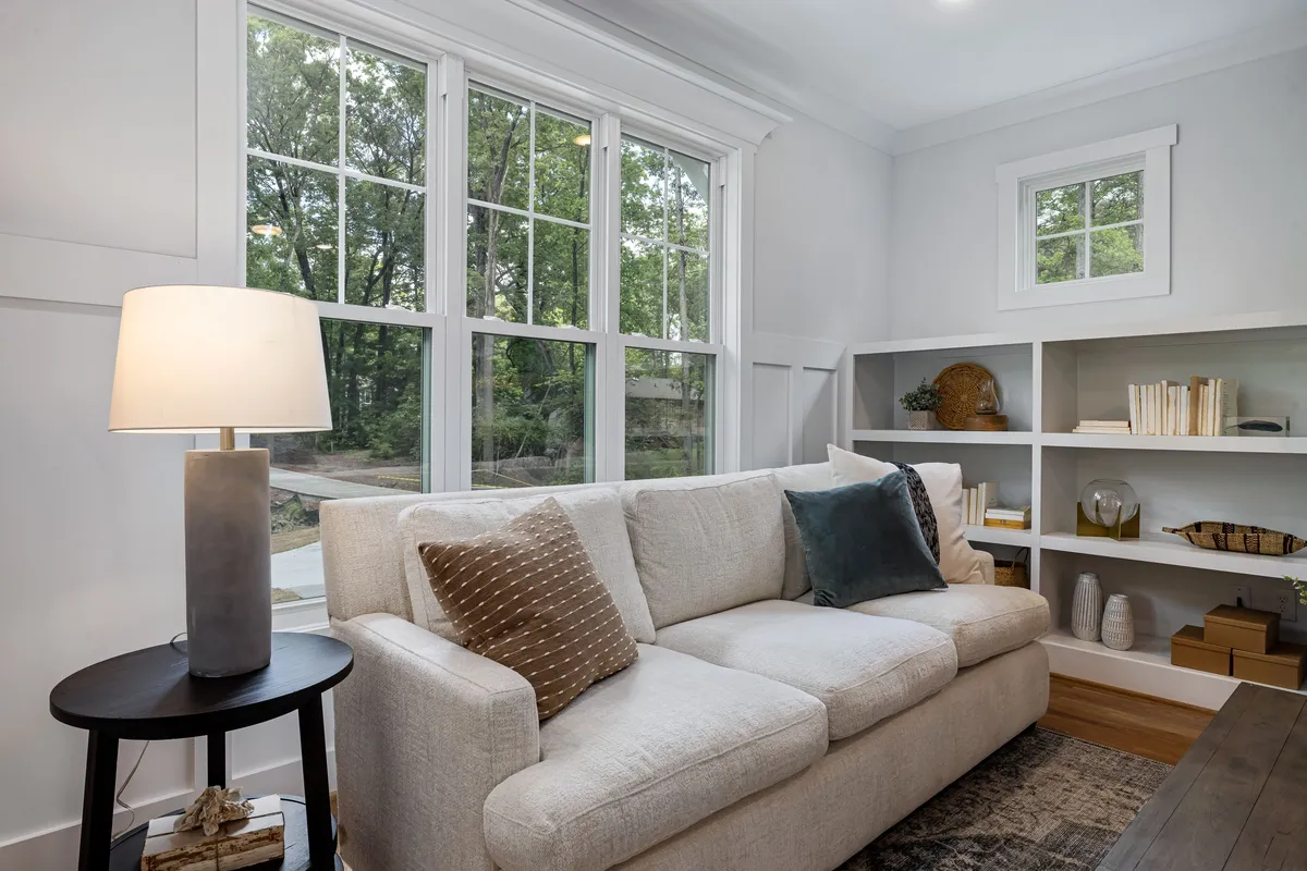 A bright living room with a sofa in front of large new windows — standard double-pane units like these are the baseline that every per-window guide prices.