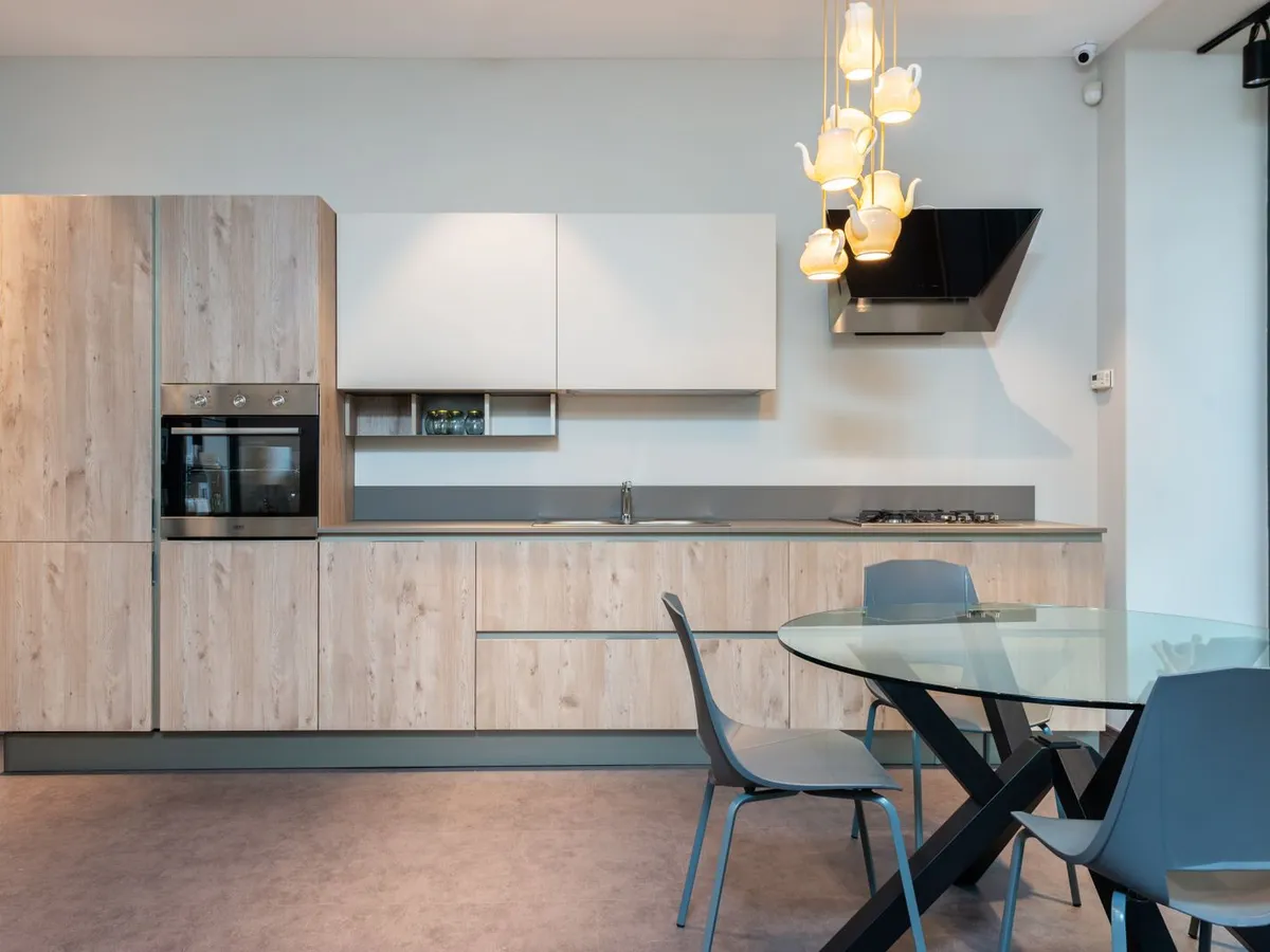 Light wood and white kitchen with a matte grey counter run and matching grey splashback panel